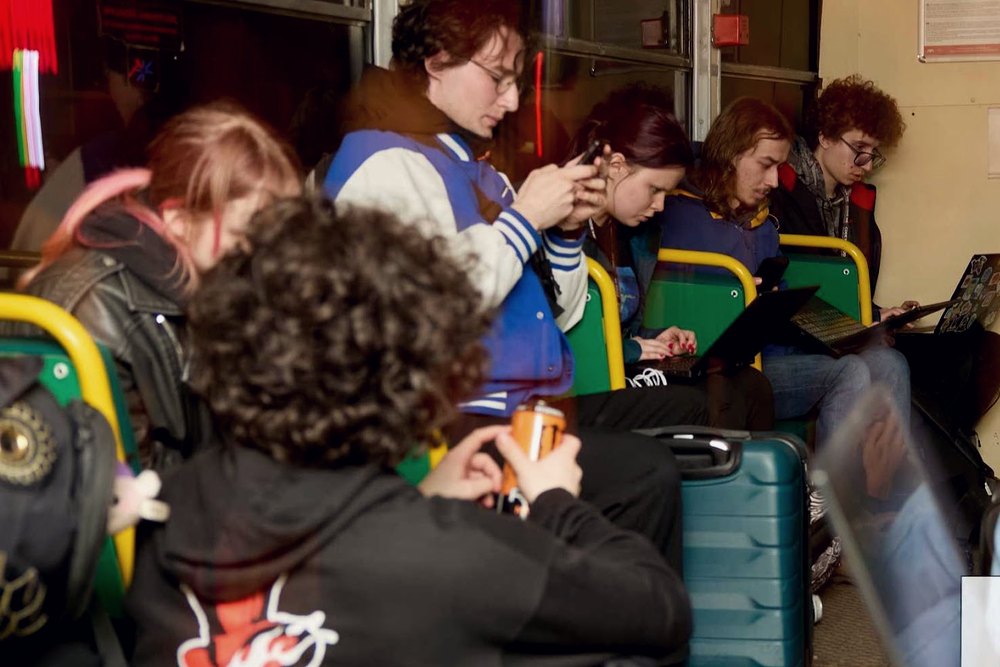 Wnętrze tramwaju pełne uczestników z laptopami