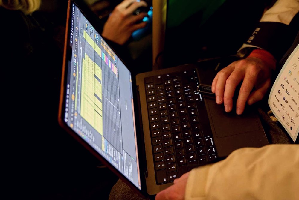 Laptop z kodem na kolanach uczestnika, w tle poręcz tramwaju
