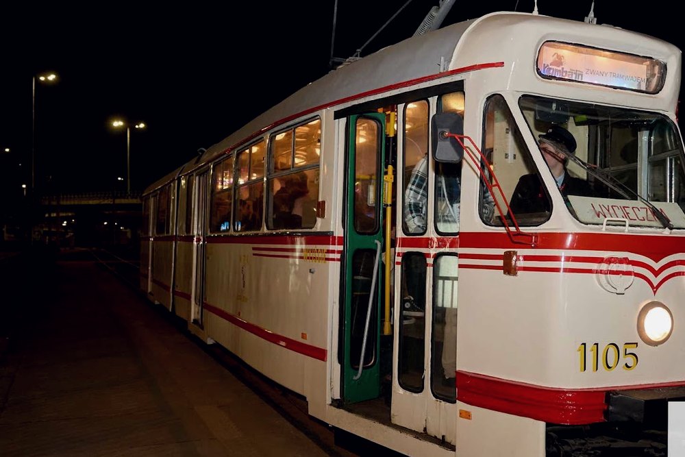 Zabytkowy tramwaj nocą na ulicy, ze świecącym wnętrzem